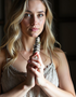 Serene woman with golden blonde hair holding a 4-inch white sage smudge stick, symbolizing sacred energy clearing and mindfulness.