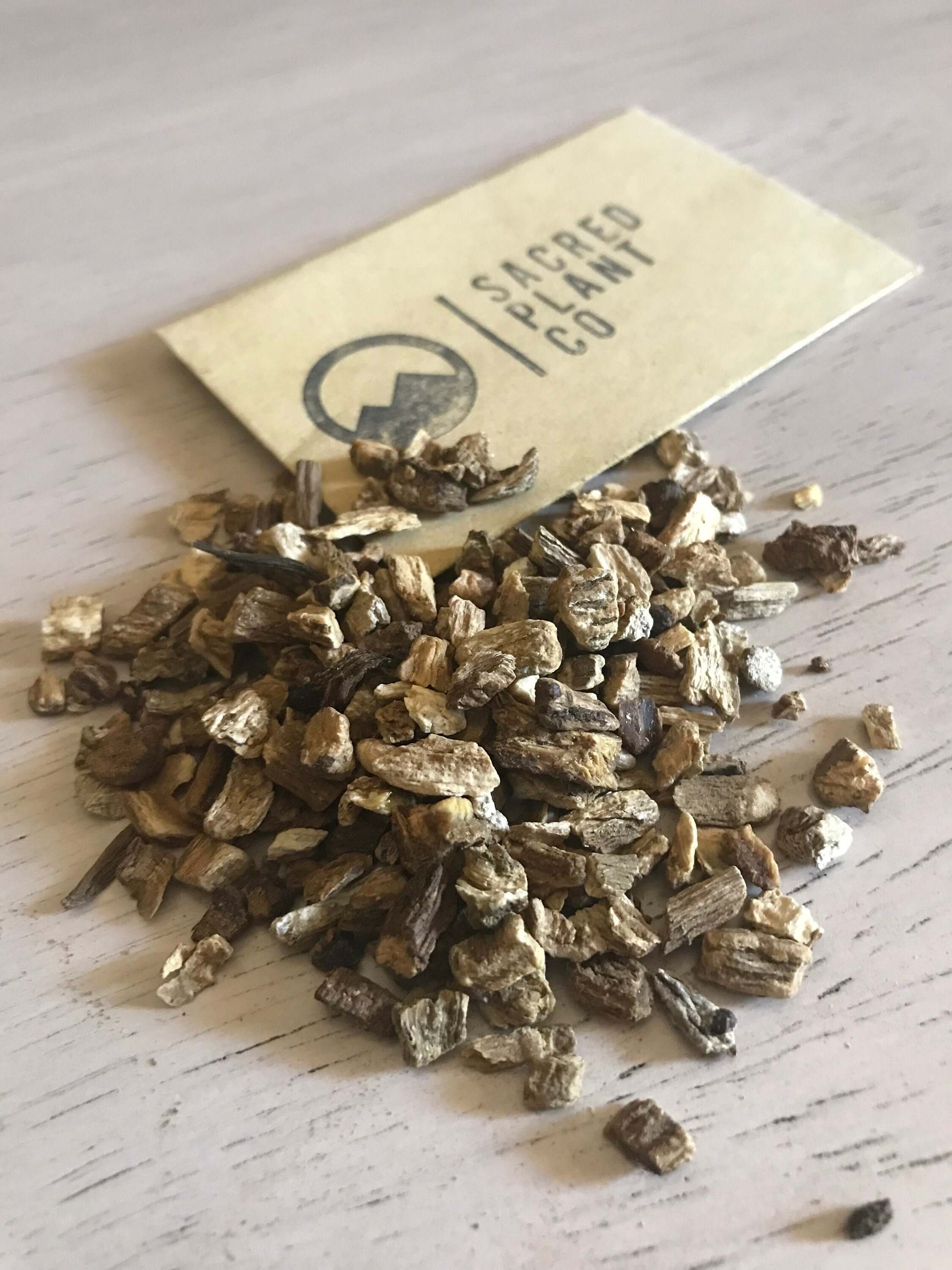 Close-up angle of Sacred Plant Co’s dried Burdock Root, positioned near branded label to emphasize premium quality.