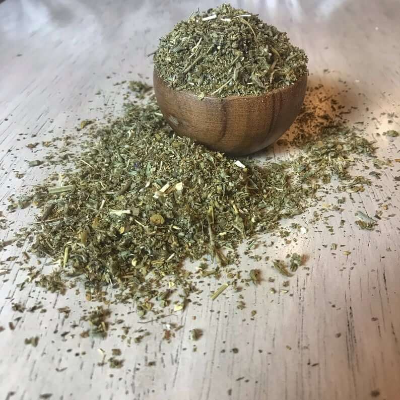 Finely textured Damiana Herb in a wooden bowl, showcasing earthy green hues on a soft light wood background, produced by Sacred Plant Co.