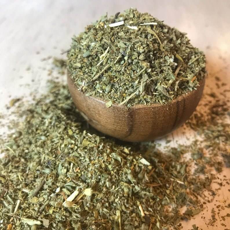 Premium, delicate Damiana Herb with varied green and brown shades, spread over a light wooden background, highlighting its natural texture at Sacred Plant Co.