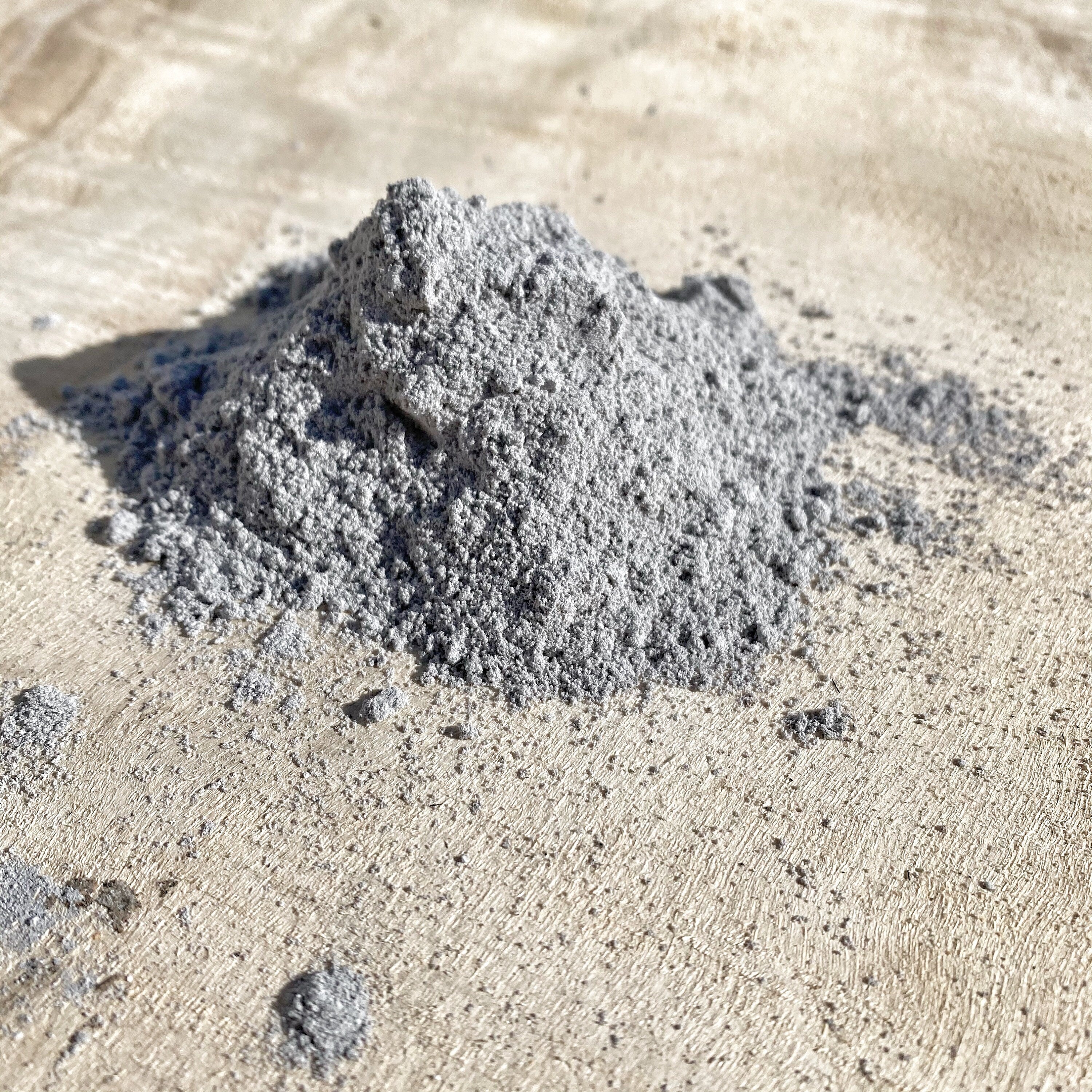 Close-up of Vibhuti Sacred Ash powder, a fine gray substance used in Hindu rituals, spread on a beige surface, symbolizing purity and spirituality.