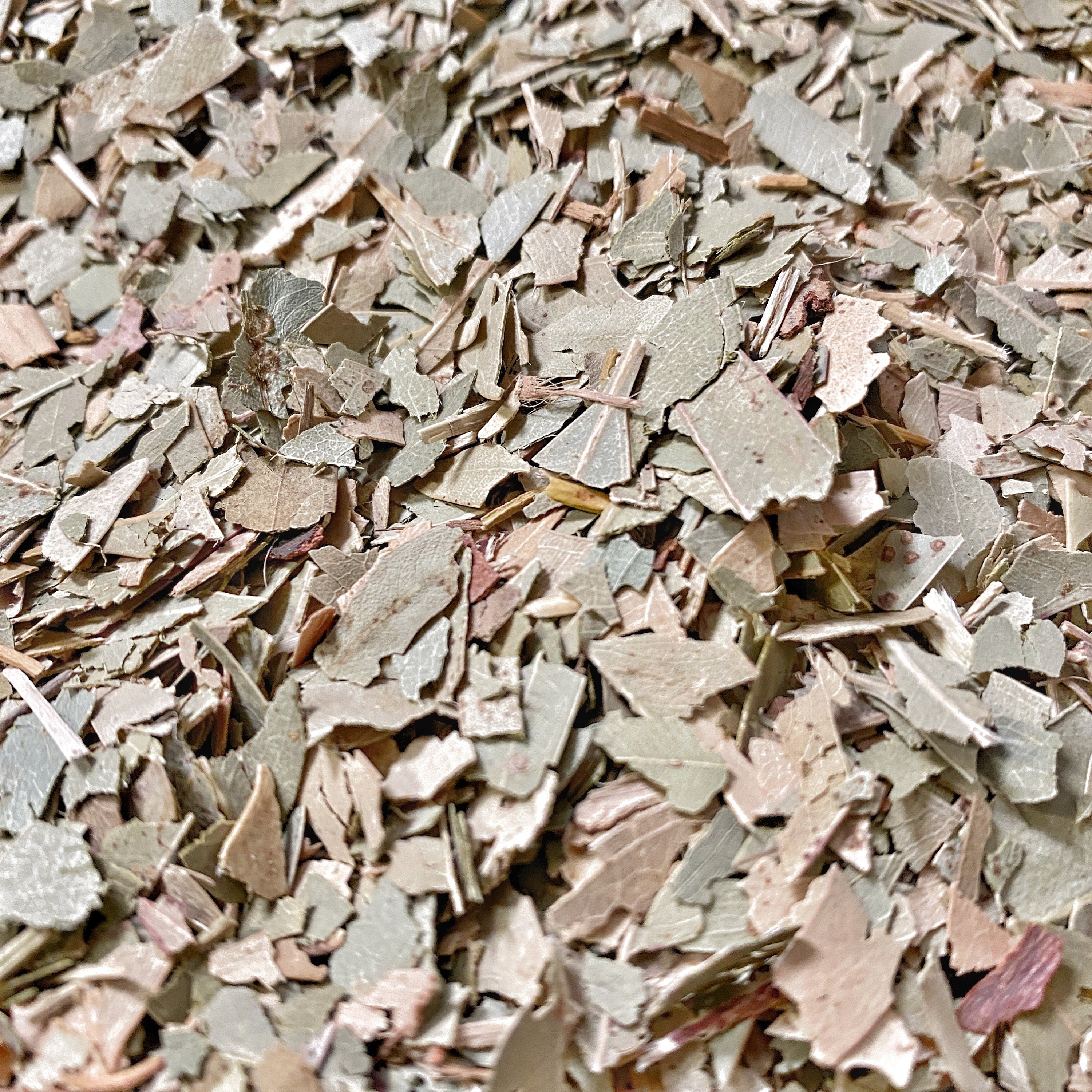 Detail of crushed eucalyptus leaves with a focus on the texture and natural variation in colors from pale green to earthy brown.A close view of chopped eucalyptus leaves, with detailed texture and color variation, suitable for herbal uses.