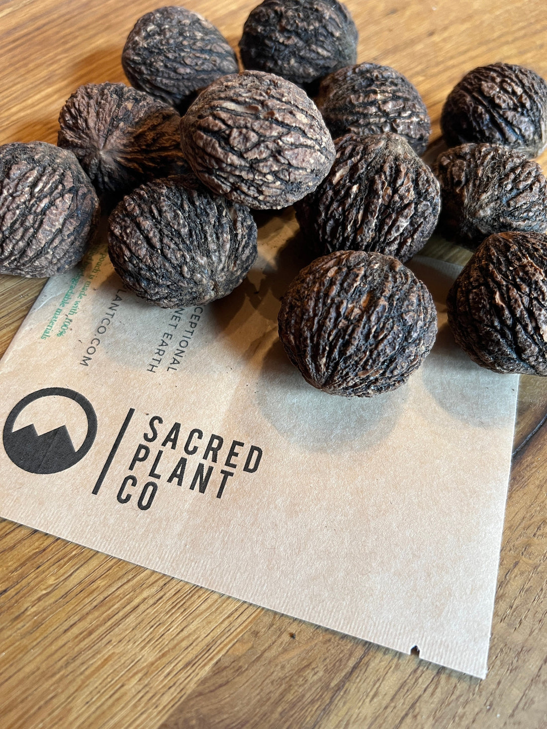 Close-up of raw black walnut seeds arranged on a branded kraft paper bag with &